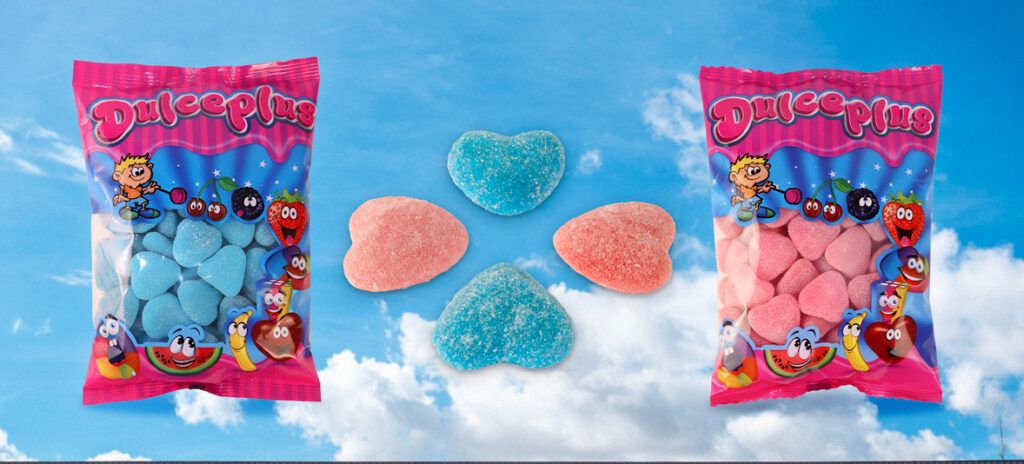 Banner de Dulceplus con bolsas de corazones rellenos azules y rosas con cobertura de azúcar (pica) sobre un fondo de cielo con nubes.